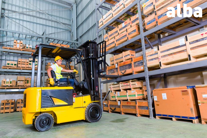 carretillero cojiendo un pallet de mercancías de una estantería con una carretilla elevadora