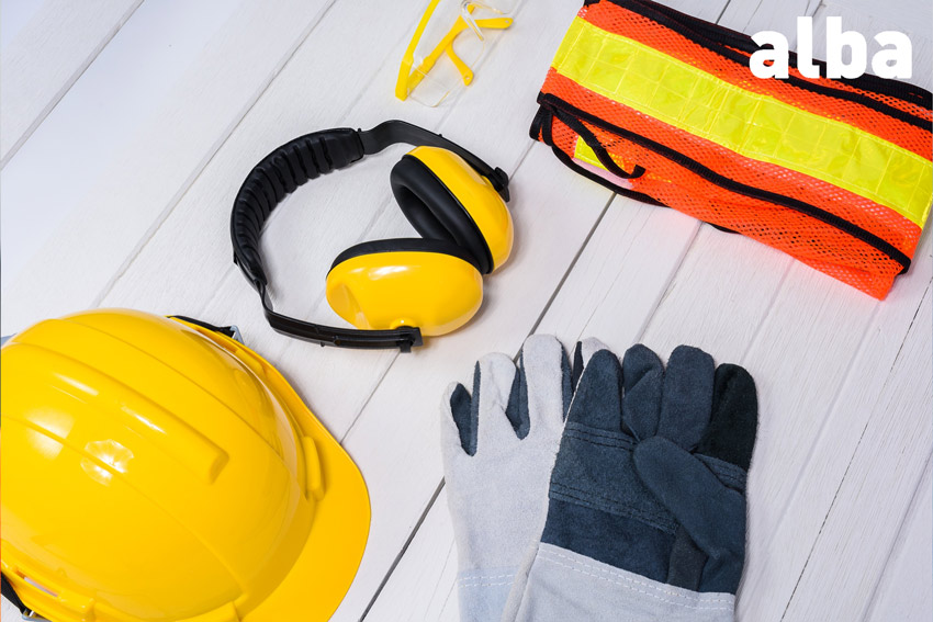 equipos epi sobre mesa de trabajo, incluyendo un casco, chaleco reflectante, guantes, gafas y auriculaes de seguridad
